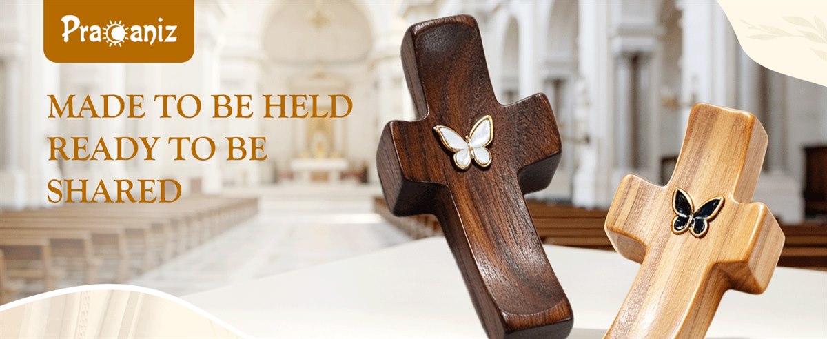 Made to be held, ready to be shared — two Pracaniz pocket crosses in black walnut and olive wood in front of a church interior